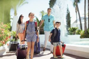 Family-with-suitcases-passing-by-fountain-in-tourist-resort-cm.jpg