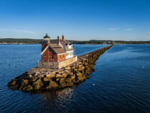 Scenic-view-of-a-historic-lighthouse-on-a-rocky-breakwater-extending-into-the-calm-blue-sea-under-a-clear-sky-cm.jpg